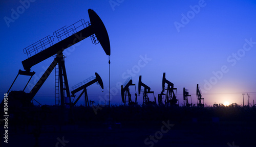 Silhouette of oil pump jacks with sunset