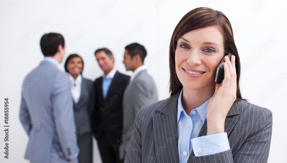 Attractive manager on phone with her team in the background Attractive manager on phone with her team in the background