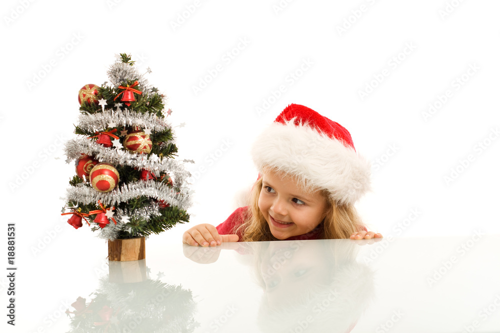 Happy kid lurking around a small christmas tree