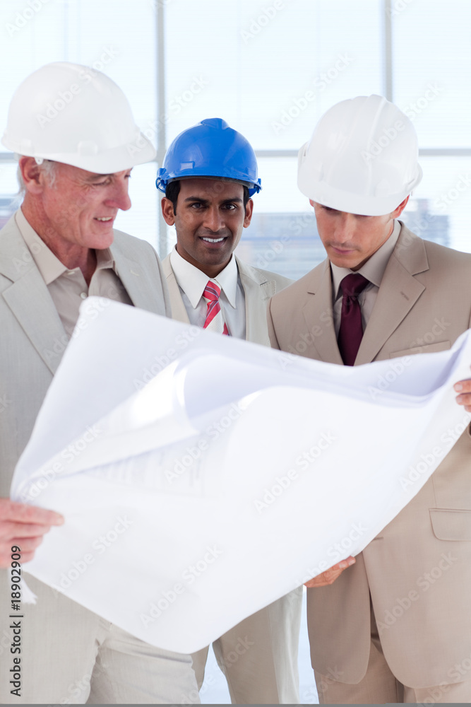 Three engineer co-workers studying plans