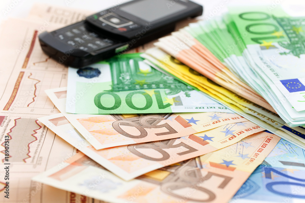 euro notes and black mobile phone on a financial newspaper euro notes and black mobile phone on a financial newspaper