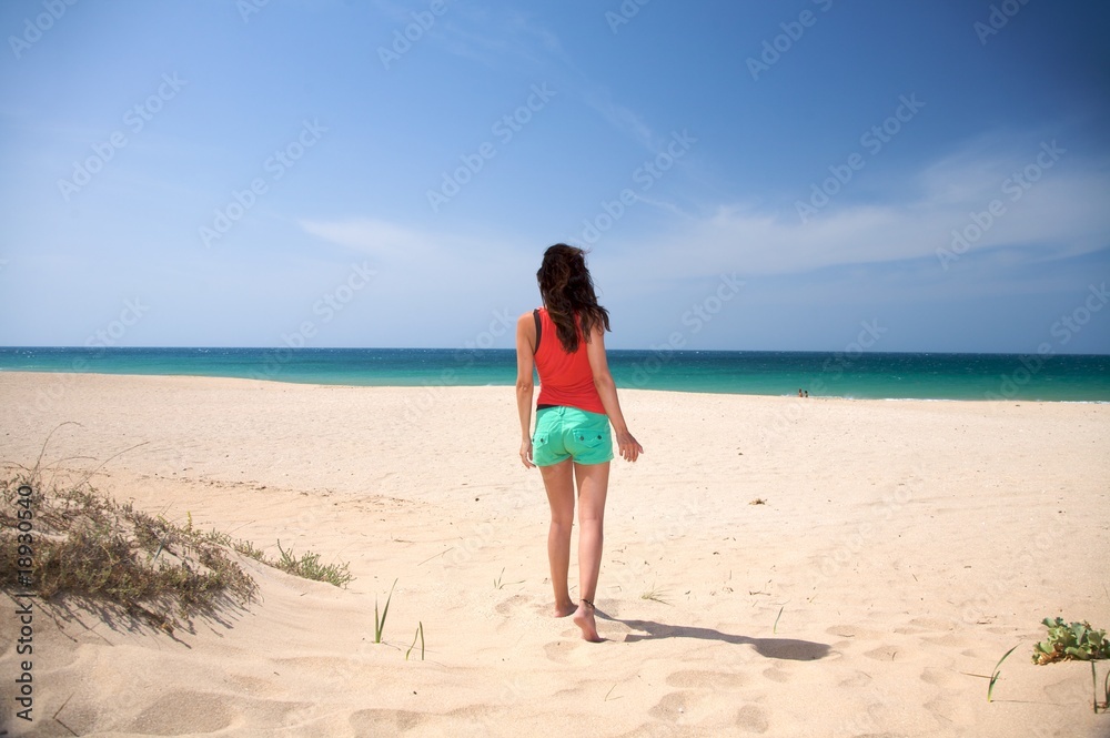 brown haired woman walking on the sand