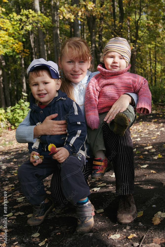 Happy family of mother and two sons in autumn forest Happy family of mother and two sons in autumn forest