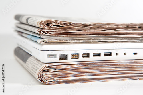 Stapel Zeitungen mit Laptop dazwischen