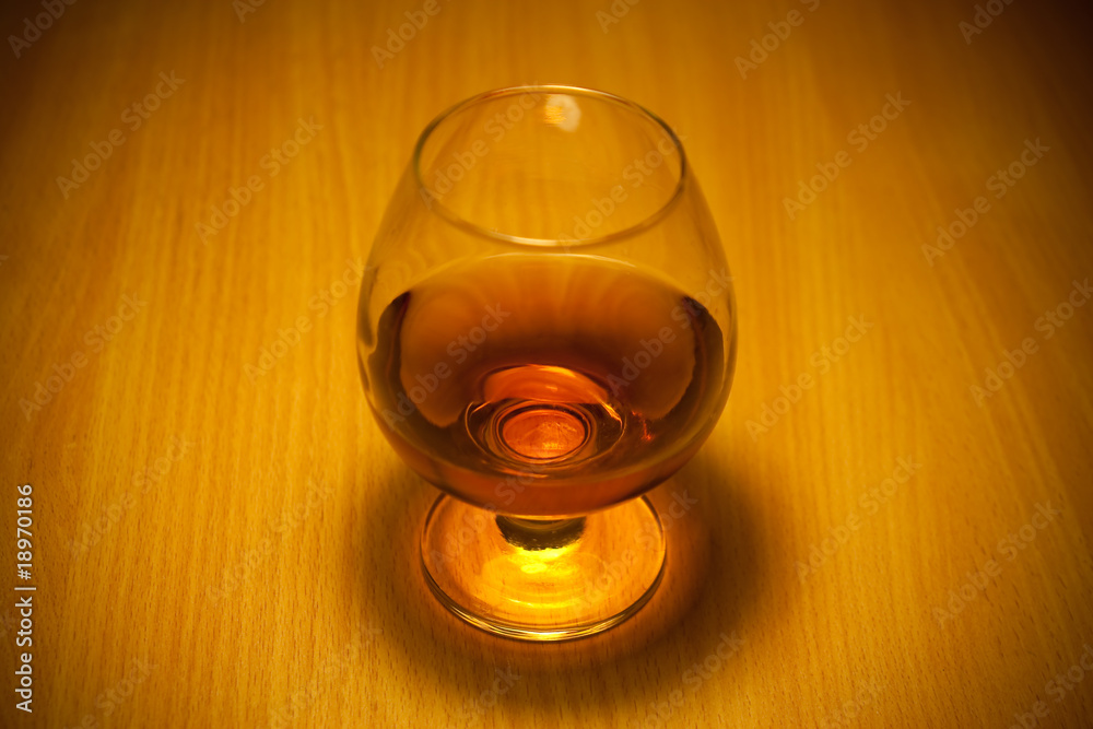 glass of cognac close-up on wooden background