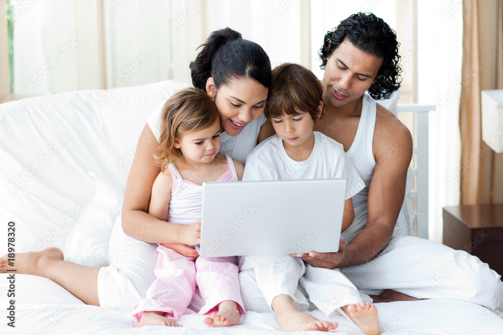 Family using a laptop on the bed