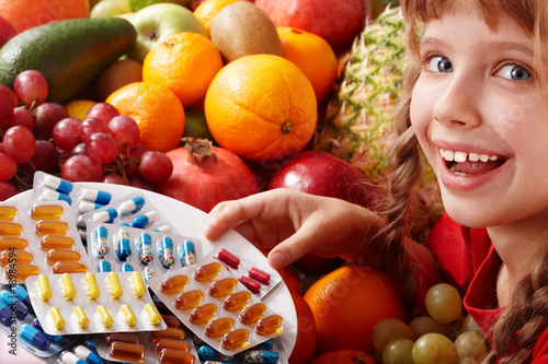 Child with fruit and vitamin pill. Health care.