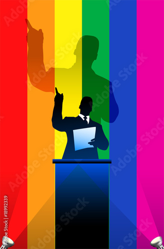 Gay Pride flag with political speaker behind a podium