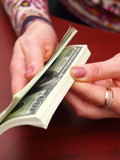 Female hands recalculate a pack of dollars on office table.