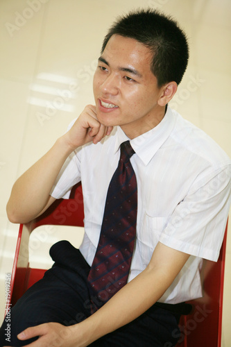 young asian businessman sitting on desk in office