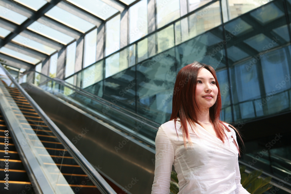 young asian business women holding mobile phone on escalator
