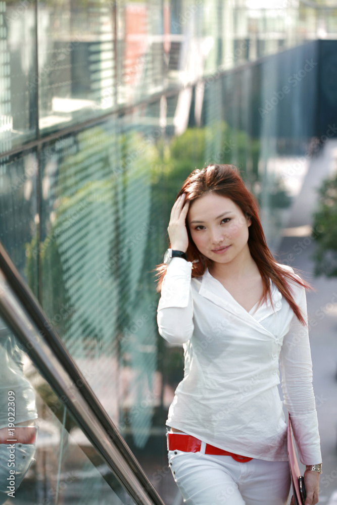 young asian businesswomen holding folder on escalator young asian businesswomen holding folder on escalator