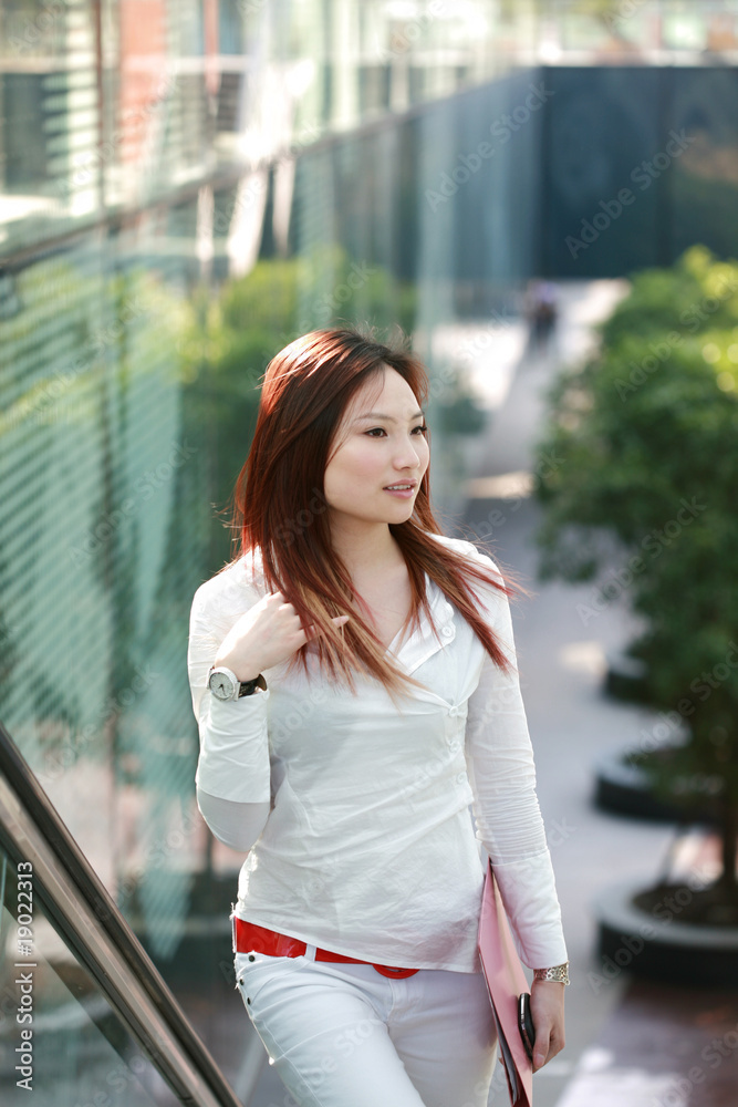 young asian businesswomen holding folder on escalator young asian businesswomen holding folder on escalator