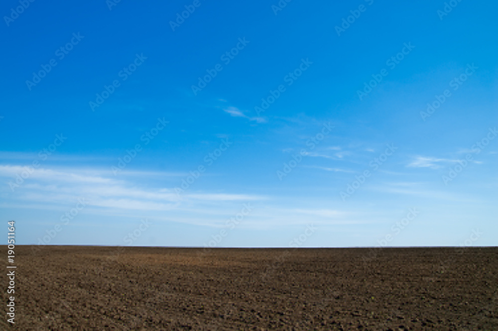 black field after harvesting under blue sky black field after harvesting under blue sky