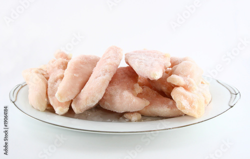 Frozen chicken thighs on platter side view