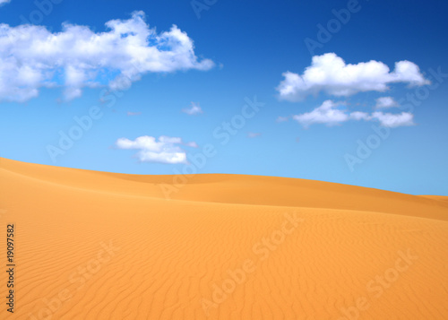 sand dunes and cumulus clouds over them  focus set in foreground