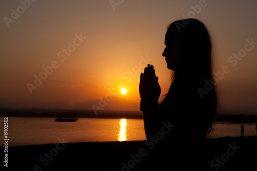 Woman silhouette with her hands raised in the sunset