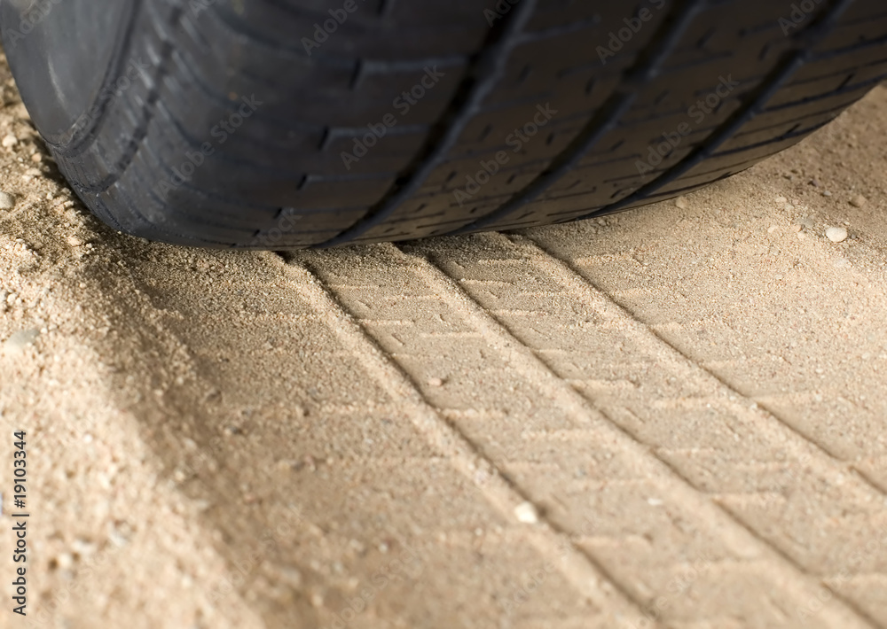 Obraz premium Black tyre and track on sand