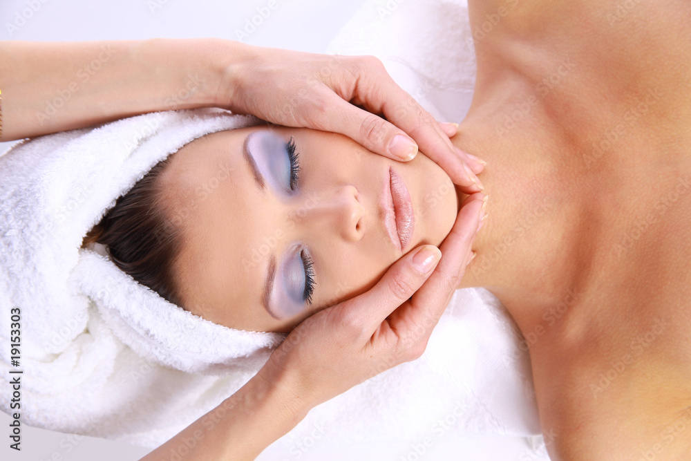 Beautiful young woman receiving facial massage.