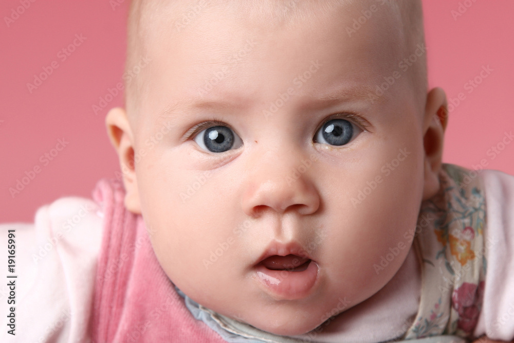 Little cute surprised child. Close-up portrait on pink backgroun