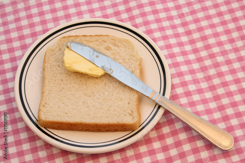 A slice of bread with butter and a knife.