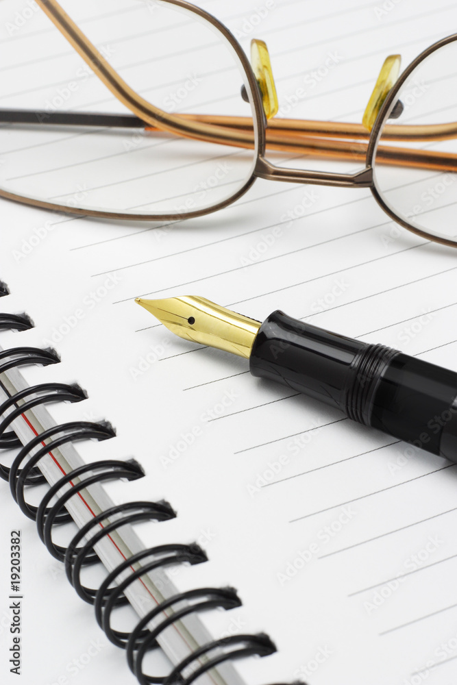 Eyeglasses and fountain pen on notebook
