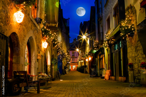 old street decorated with lights and full moon photo