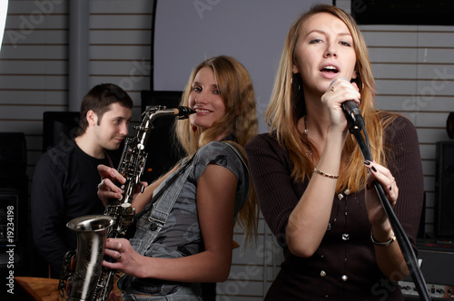 two young females sign the song and play on saxophone photo