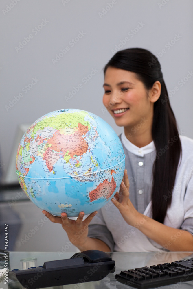 Smiling asian businesswoman looking at a globe Smiling asian businesswoman looking at a globe
