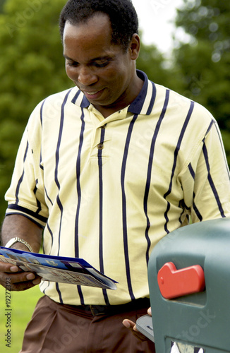 African American man getting mail from mailbox
