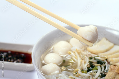 A pair of chopsticks holding a fishball from koay teow soup