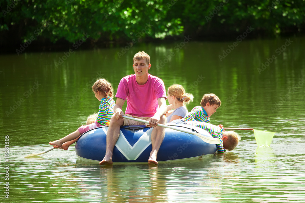 Children and adults float on an inflatable boat in a sunny day