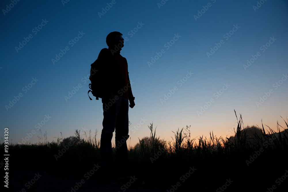 Silhouette of the man with a backpack against the dark sky