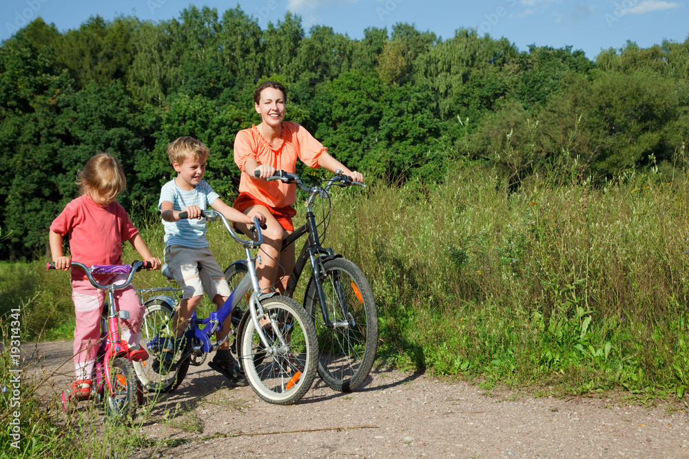 Mother with son and daughter ride bikes outside the city