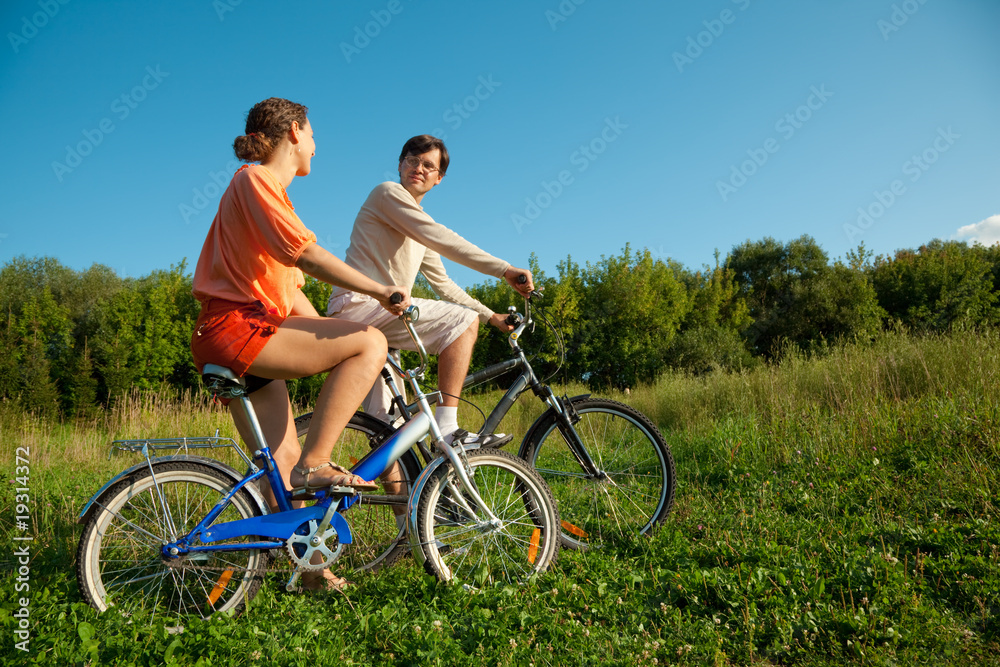 girl and man go for drive on bicycles in a sunny day
