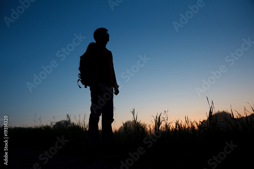 Silhouette of the man with a backpack against the dark sky