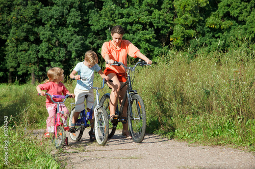 Mother with son and daughter ride bikes outside the city