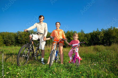 Parents with daughter on bicycles in park a sunny day.