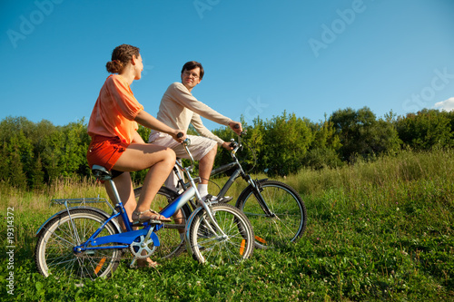girl and man go for drive on bicycles in a sunny day