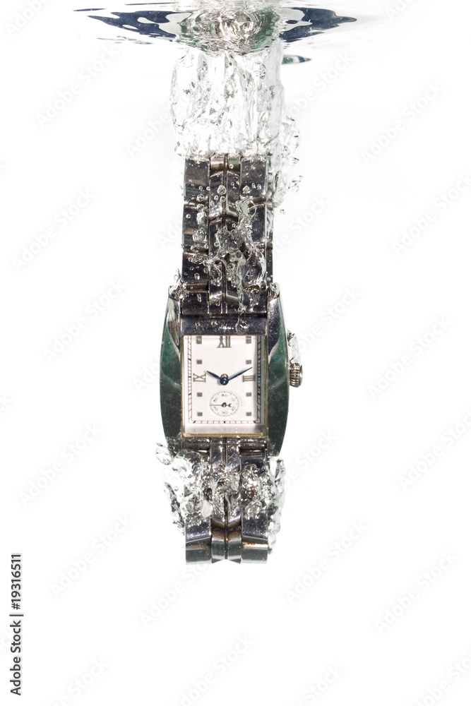 A stainless steel analog watch falling into clear water