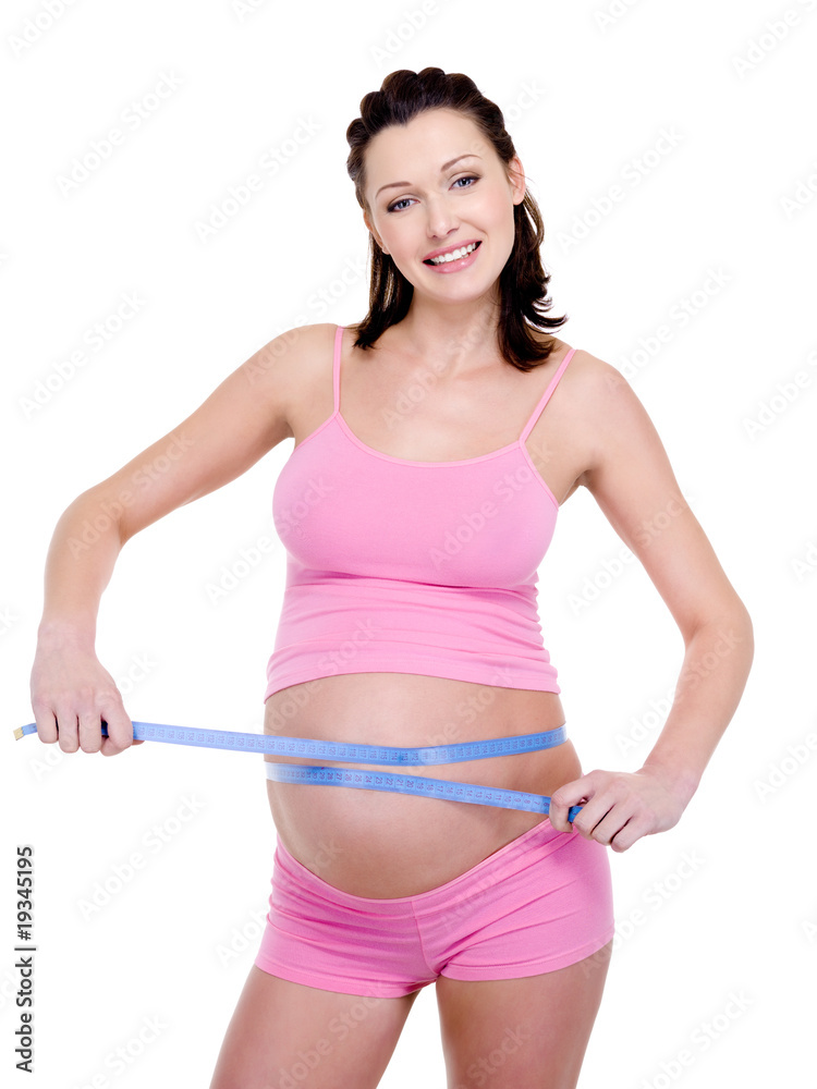 Pregnant woman measures her tummy on a white Pregnant woman measures her tummy on a white