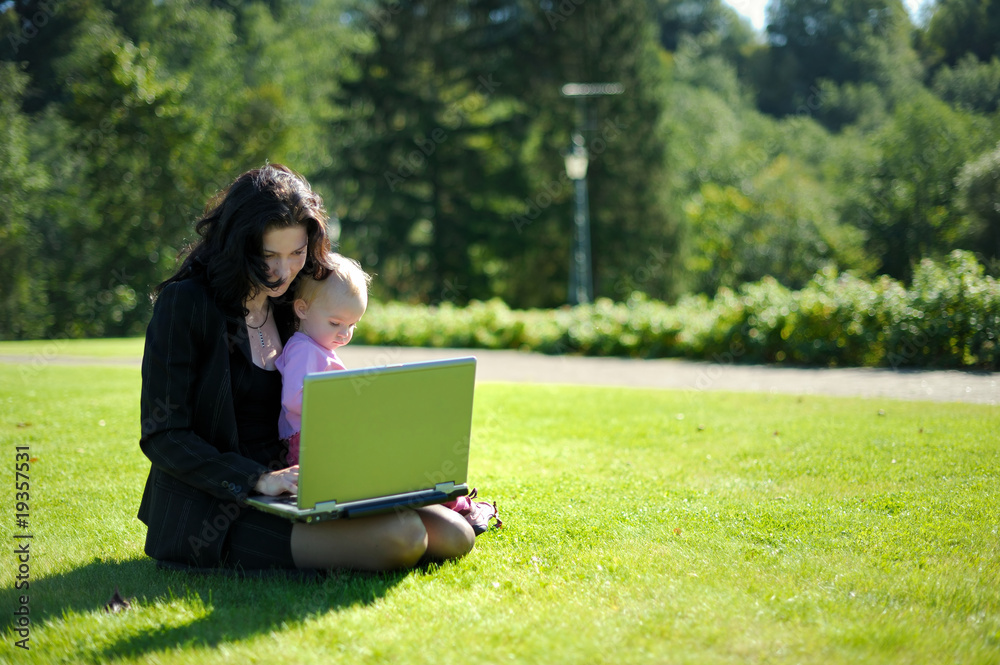 Young lady with a baby and a notebook in a park Young lady with a baby and a notebook in a park