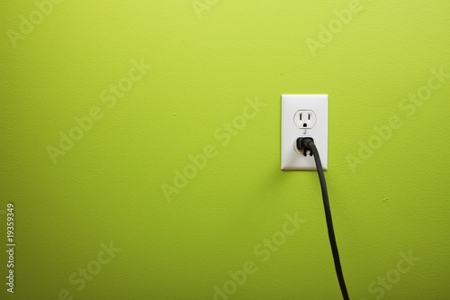 black cable plugged in a white electric outlet