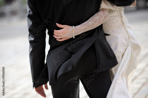 Bride girdling groom's waist photo