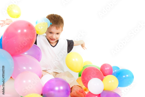 young boy playing with balloons over white