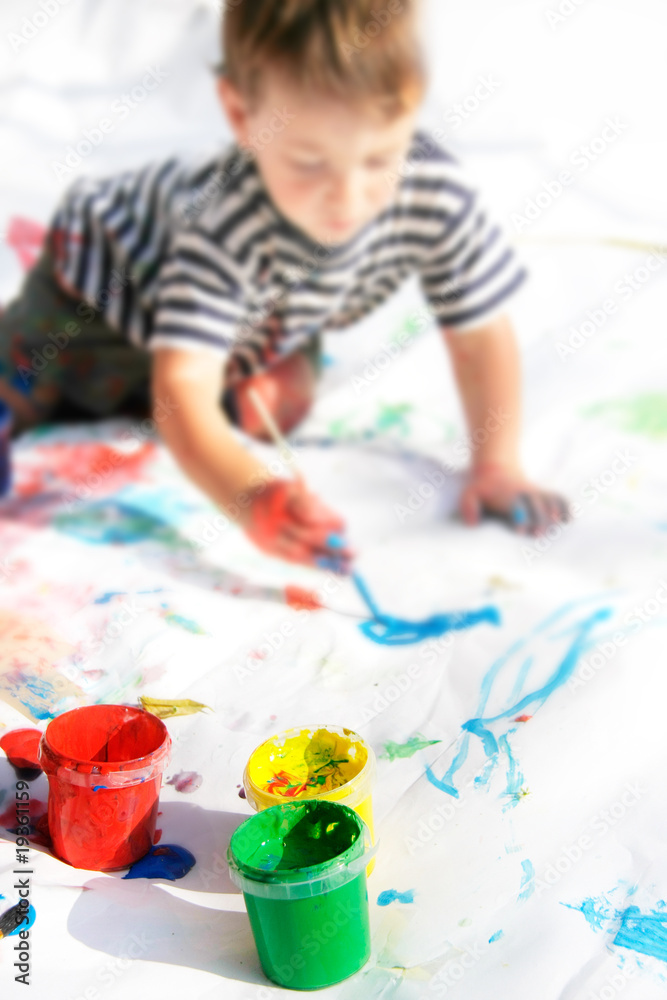 Naklejka premium young boy painting, focus on cans