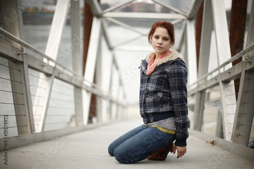 Young woman kneeling on bridge. © Peter Kim