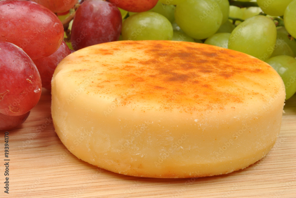 cheese and some sweet grapes in the background cheese and some sweet grapes in the background
