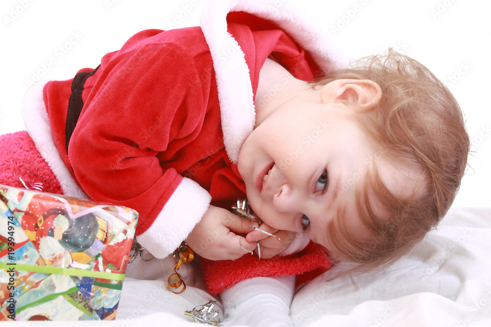 Little happy girl in red santa's clothes with present