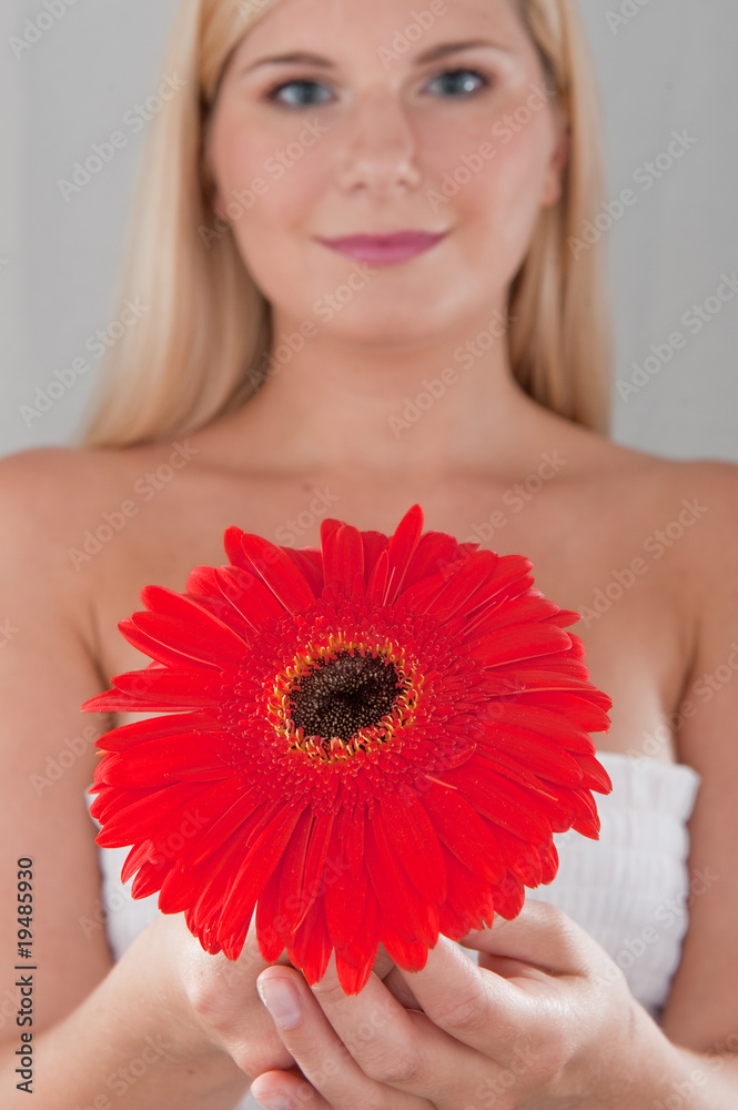 Young healthy woman with pure skin and red flower